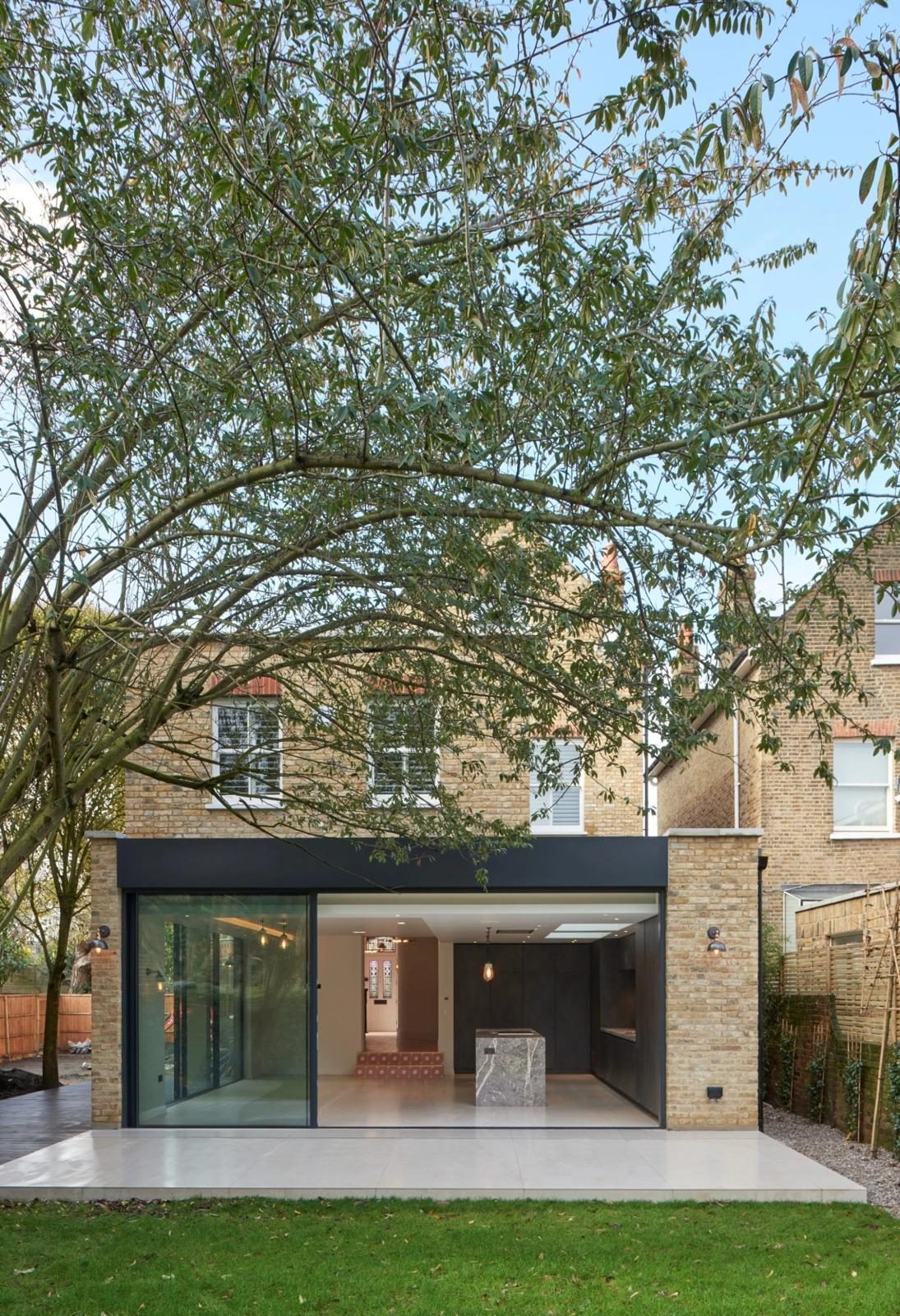The rear extension from the garden — full-width glazing under a flat zinc-line fascia