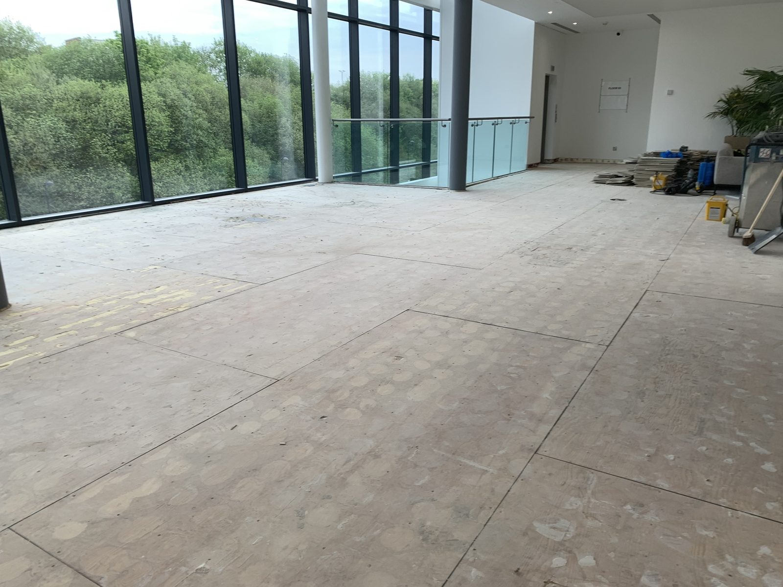 Strip out — old tiles lifted and stacked for removal on the atrium walkway