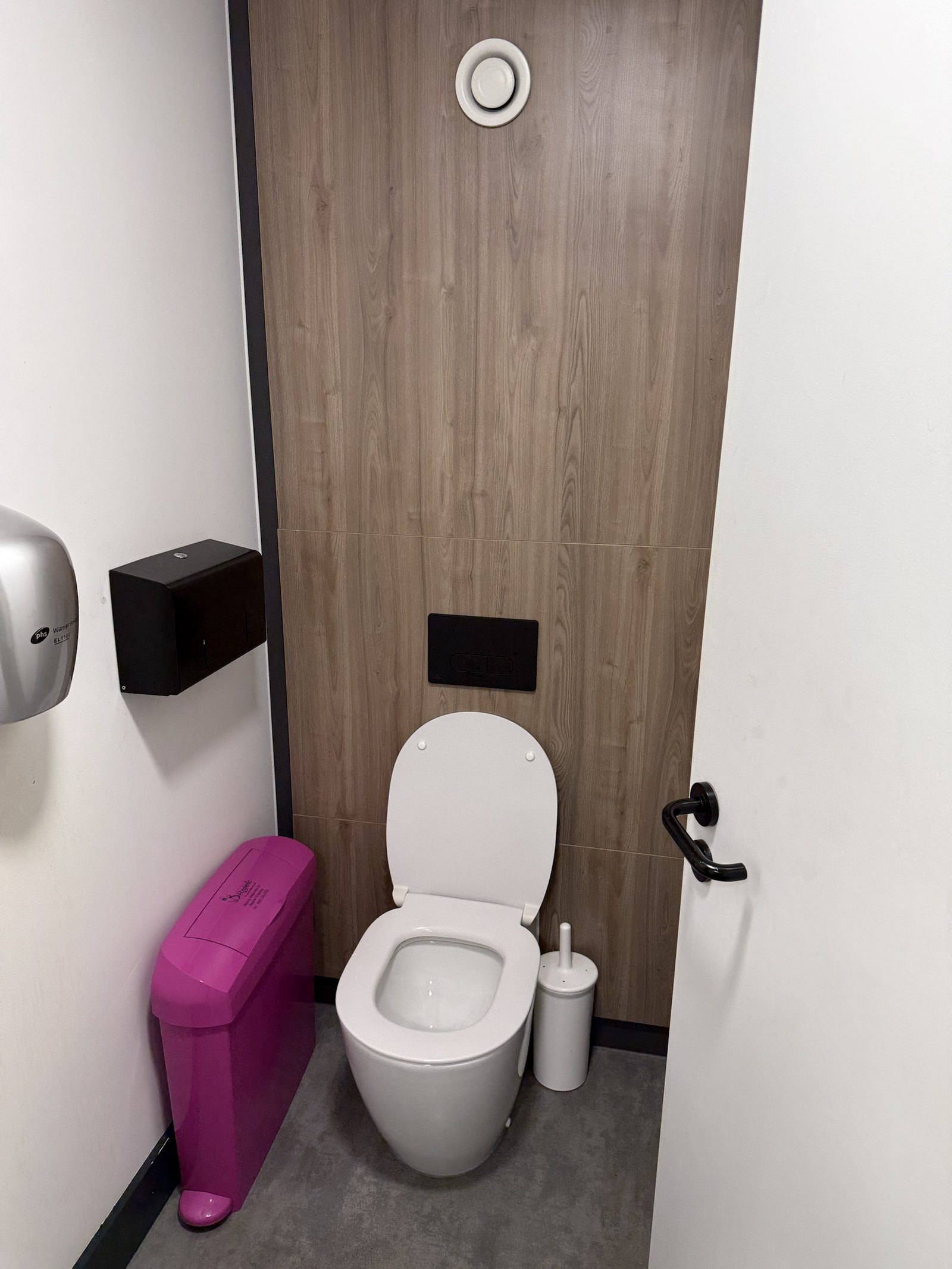 Accessible WC — wood-effect panelling, concealed cistern and black fittings